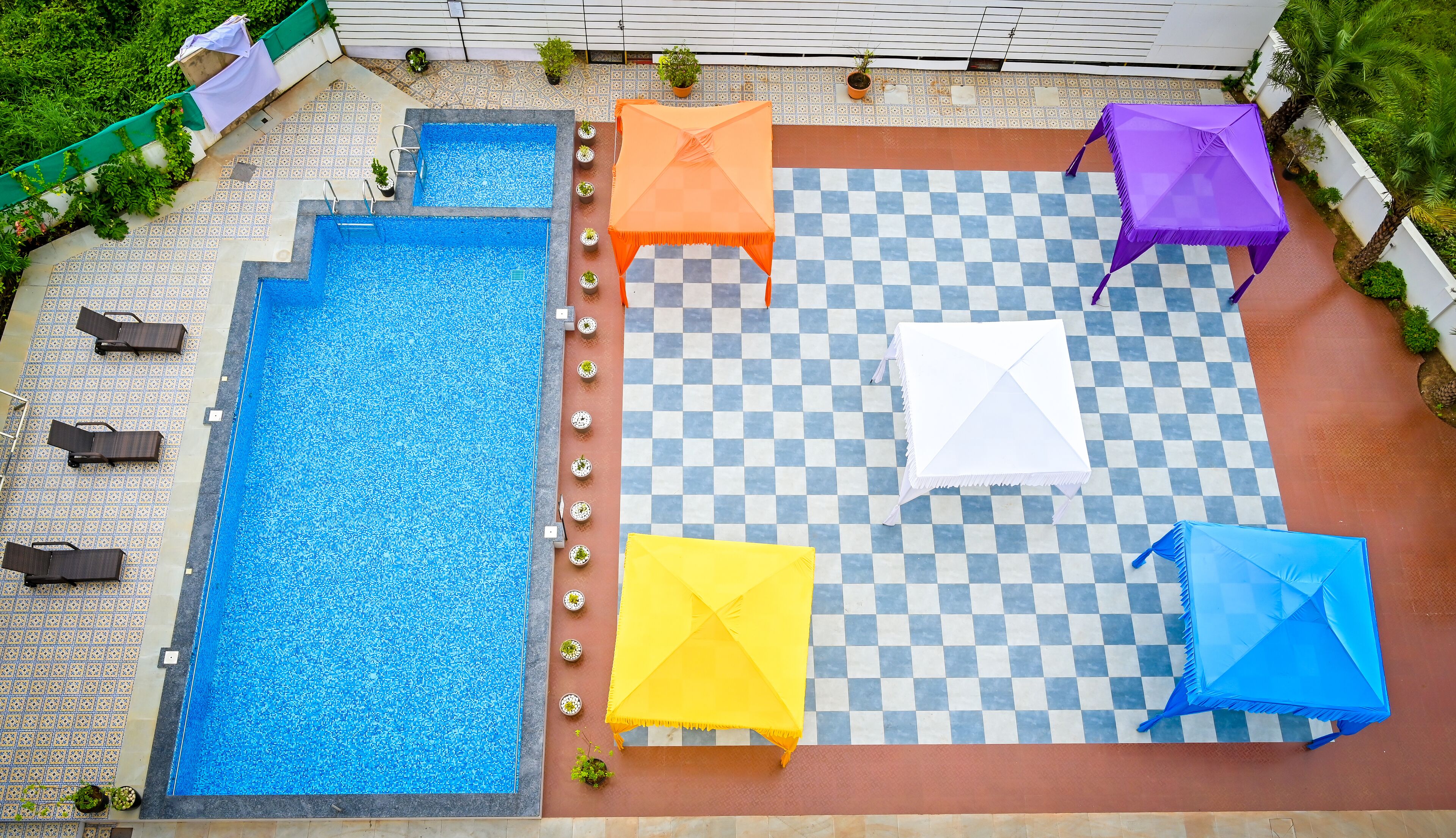 A rooftop swimming pool with multiple lounge chairs and umbrellas.