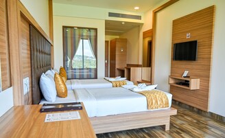 Habitación de hotel con una cama grande, un escritorio, un televisor y vista a zonas verdes.