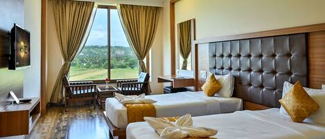 A hotel room with two beds, a TV, a desk, and a view of a green landscape.