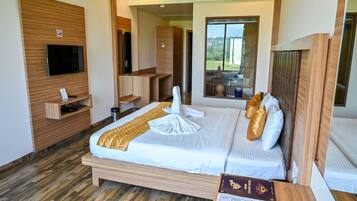 A hotel room with a bed, a TV, a wooden desk, and a window with a view.