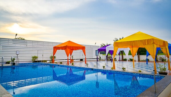 A swimming pool with a checkered deck, surrounded by colorful canopies.