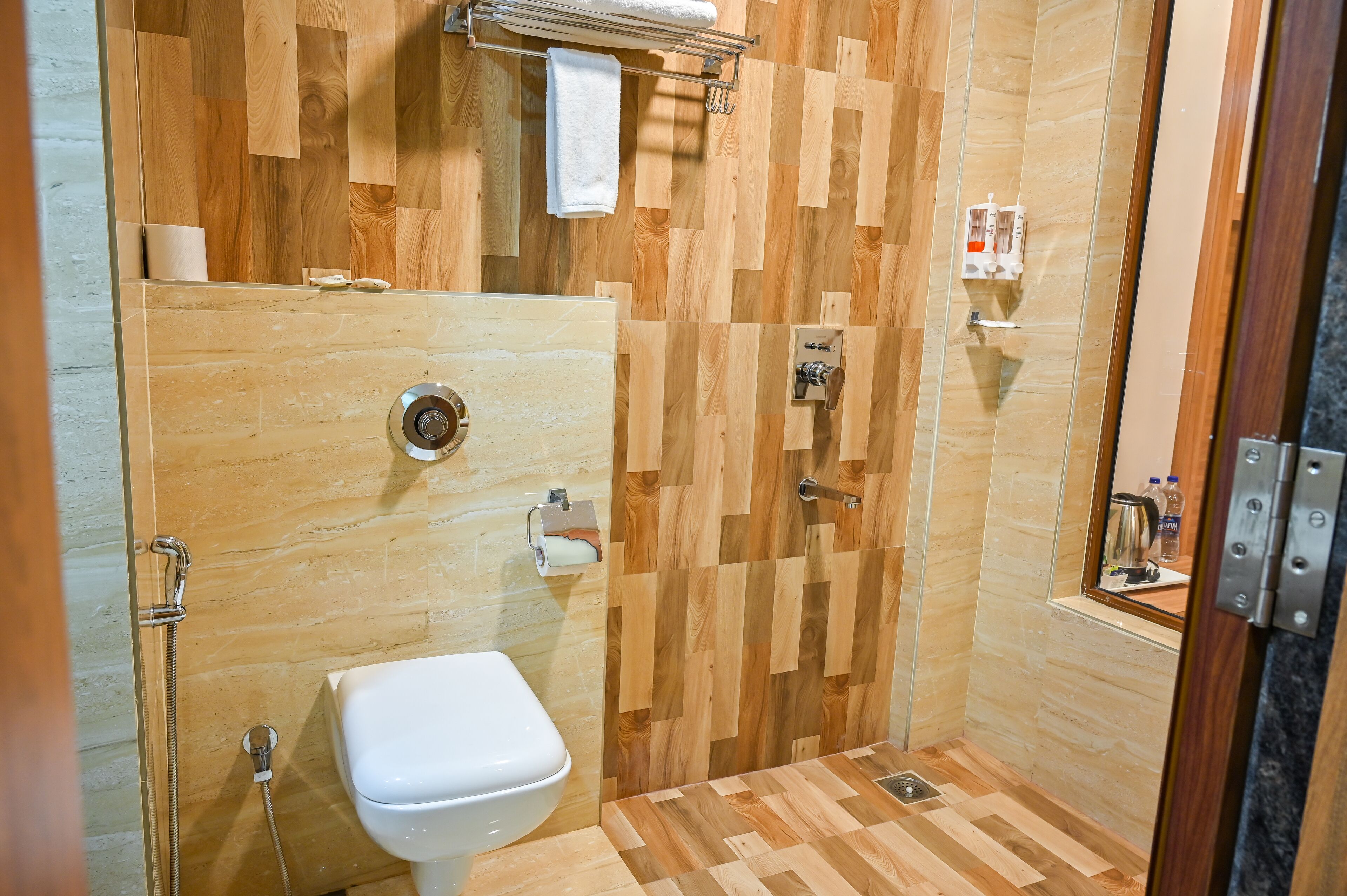 Une salle de bain moderne avec un mur décoré en bois, des toilettes blanches et un espace douche.