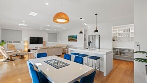 A modern kitchen with a central island, bar stools, and a dining table. - 108 Madaffari Drive - bring your boat! (EXMOUTH)