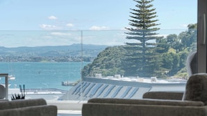 A room with a view of a body of water, a chair, and a table. - The Oceanside Belle Mt Maunganui (Mt Maunganui)