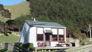 Une petite cabane à un seul étage, dotée d’un porche couvert et d’une cheminée en pierre.