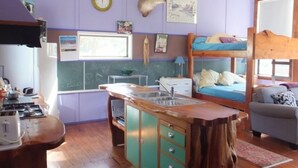 Une chambre compacte comprenant un coin cuisine, un lit superposé et un espace salon.