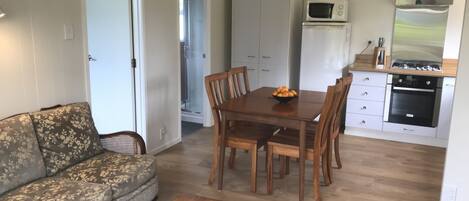 Una sala de estar con un sofá, una mesa de centro y un comedor con mesa y sillas. Cuenta con una cocina equipada con microondas, horno y alacenas.