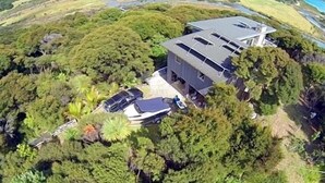 A modern house surrounded by dense greenery, with a clear view of the surrounding landscape. - Barrier Headquarters entire complex. Unobstructed 270 degree view beach/mountain (Medlands Beach)