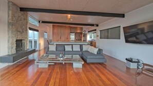 A spacious living room with a stone fireplace, a large gray sectional sofa, and a coffee table. - Barrier Headquarters entire complex. Unobstructed 270 degree view beach/mountain (Medlands Beach)