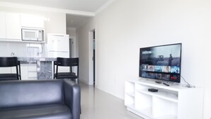 A modern living room with a flat-screen TV, a leather sofa, and a white entertainment unit. - 211, 2-bedroom apartment near the beach (Bombas)