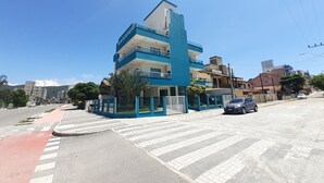 A multi-story building with a blue facade, a gated entrance, and a parking area. - 211, 2-bedroom apartment near the beach (Bombas)