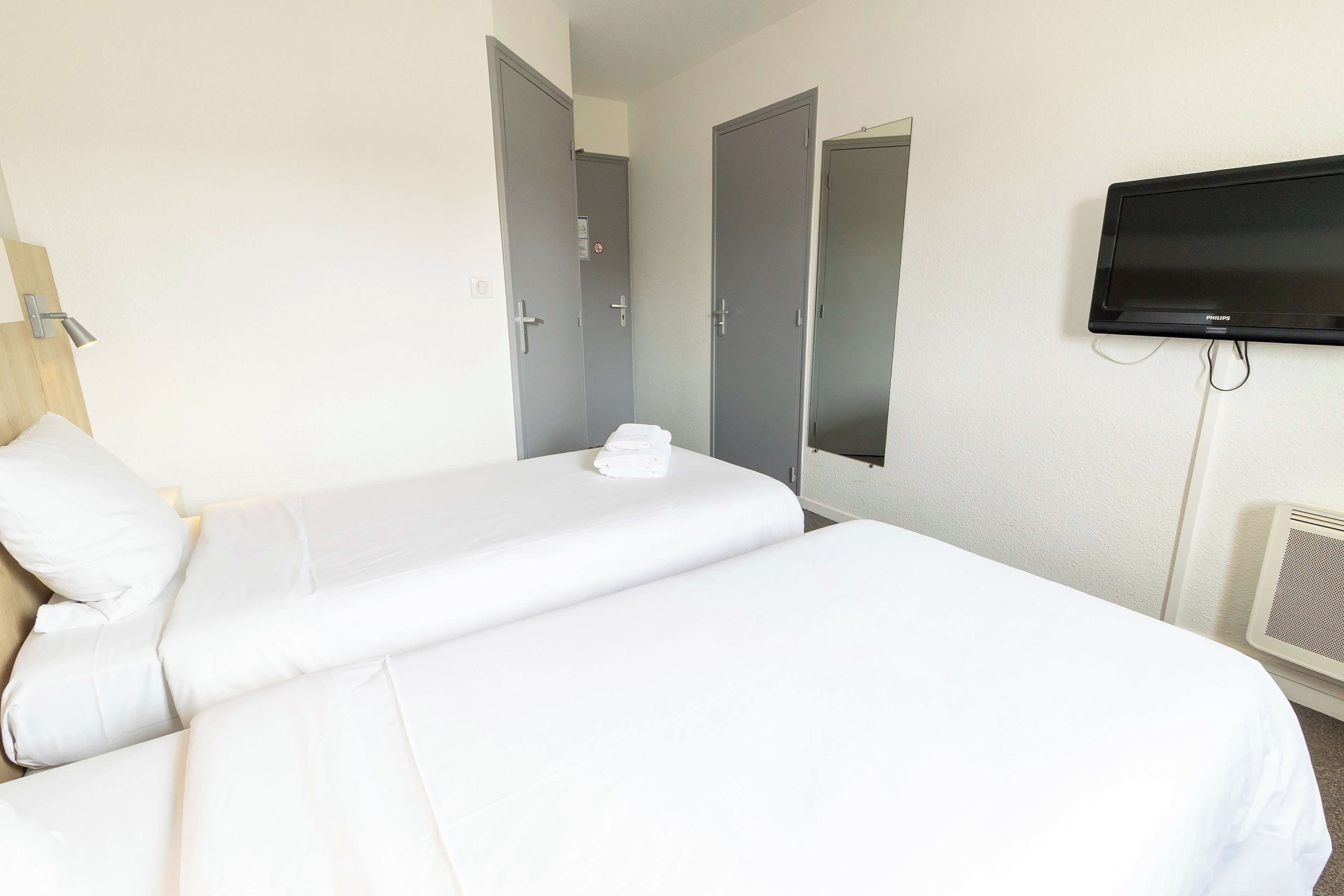 Una habitación de hotel con una cama, un televisor y una puerta.