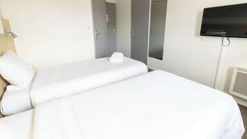 Una habitación de hotel con una cama, un televisor y una puerta.