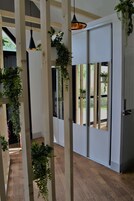 Un interior moderno con vigas de madera, una puerta corrediza y plantas colgantes.
