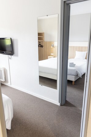 Una habitación de hotel con una cama, un televisor y un espejo que refleja el cuarto.