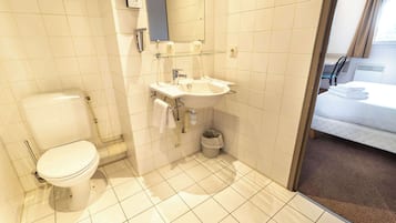 Un baño con inodoro, lavabo y un pequeño cubo de basura.