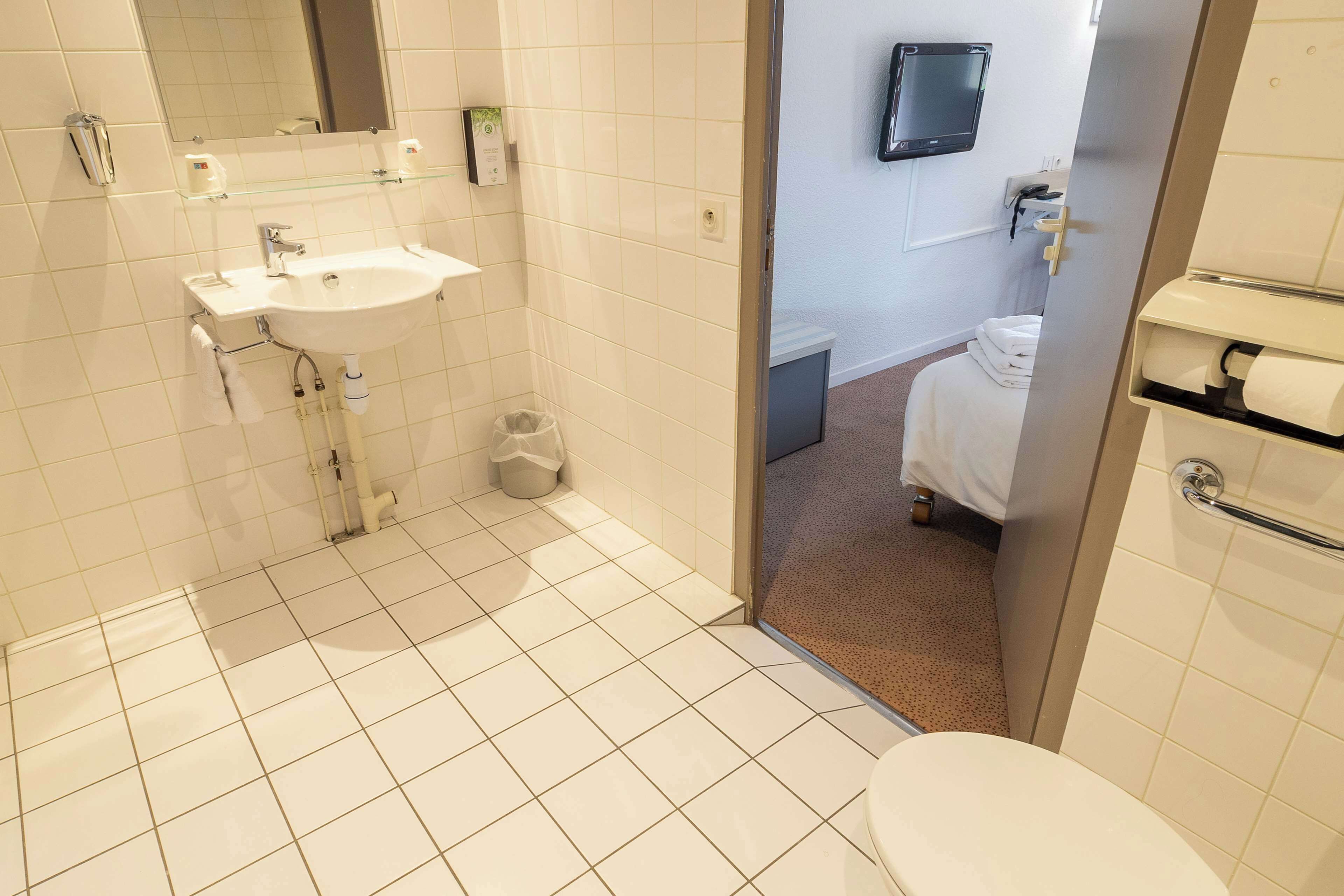 Ein modernes Badezimmer mit Waschbecken, Spiegel und Toilette in Weiß.