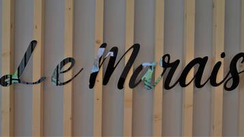 A wooden slat wall with the word "Le Marais" in black cursive letters.