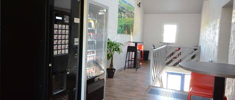 Un intérieur moderne comprenant un distributeur automatique, une plante en pot et un coin repas avec une table et des chaises.