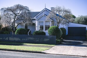 Une maison de plain-pied avec un garage, une clôture en piquets et une pelouse bien entretenue.