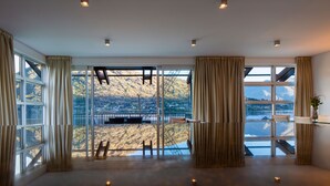A spacious room with large windows offering a view of a mountainous landscape. - Marina 2 Bdrm Apartment with Views (Frankton)