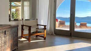 A spacious room with a large sliding glass door leading to a balcony with a view of the sea. - Villa Savannah (Mykonos)