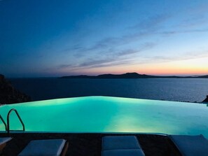 A infinity pool with a view of the sea and distant mountains at sunset. - Villa Savannah (Mykonos)