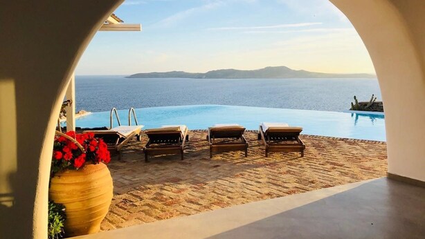 An infinity pool with lounge chairs and a view of the sea. - Villa Savannah (Mykonos)