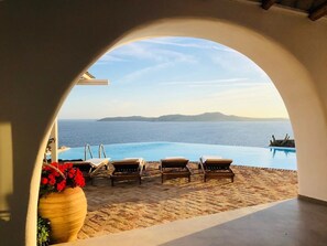 An infinity pool with lounge chairs and a view of the sea. - Villa Savannah (Mykonos)
