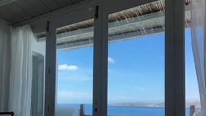 A room with a large sliding glass door leading to a balcony with a view of the sea. - Villa Savannah (Mykonos)