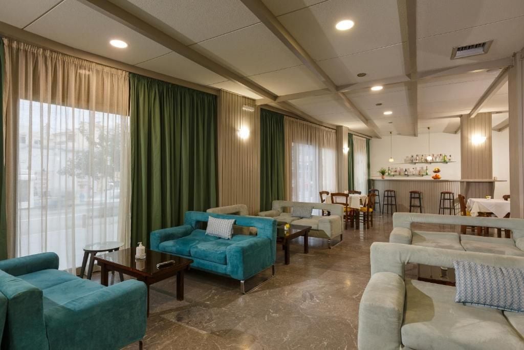 A hotel lobby with multiple seating areas, a bar, and a view of the outdoors.