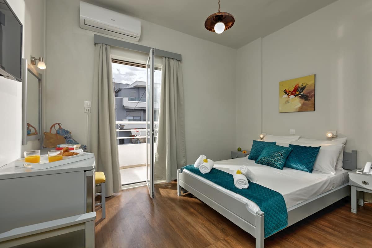 A hotel room with a bed, bedside table, and a desk with breakfast items.