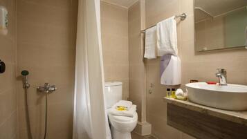 A bathroom with a shower, toilet, sink, and a mirror.