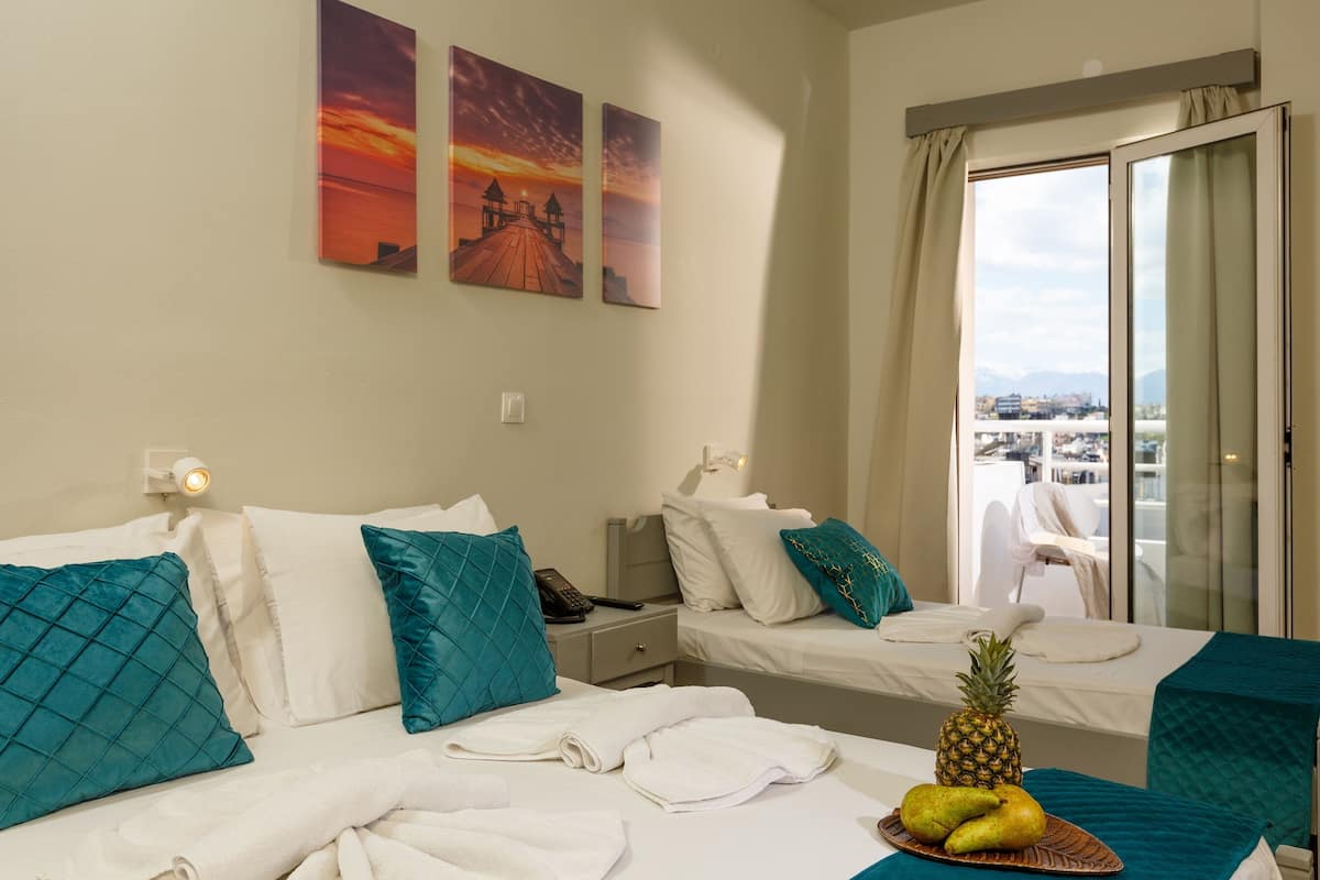 A hotel room with two beds, teal pillows, a pineapple, and a fruit plate on the bed.