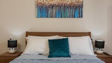 A hotel room with a bed, two bedside tables with lamps, and a painting on the wall.