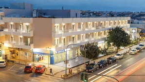 Un hotel de varios pisos con balcones, estacionamiento y vistas a la ciudad.