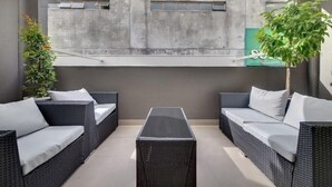 A modern outdoor seating area with wicker furniture and a central table. - Fantastic Cuba apartment (Wellington CBD)
