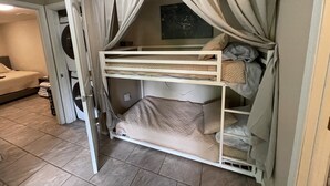 A bunk bed with curtains, a washing machine, and a bed with a blanket.