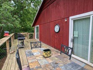 Un bâtiment rouge doté d’un patio comprenant un barbecue, une horloge et une nichoir.