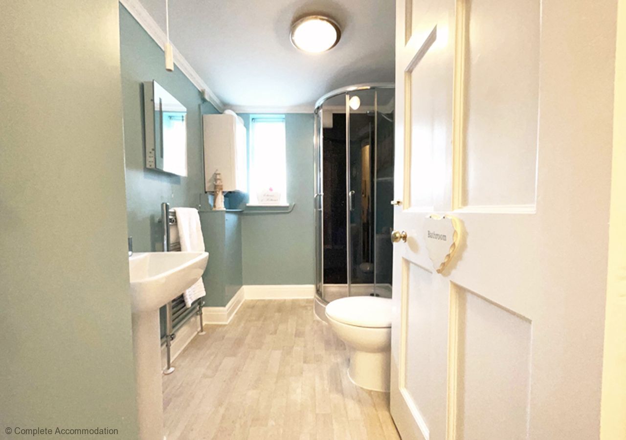 Un baño con lavamanos, inodoro y cabina de ducha de vidrio.