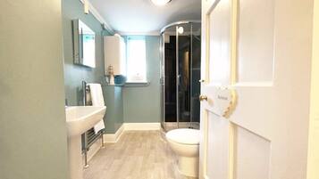 Un baño con lavamanos, inodoro y cabina de ducha de vidrio.