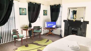 Une chambre d’hôtel avec un lit, une télévision, une cheminée et un fauteuil vert.