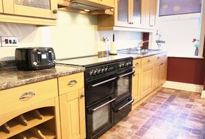 Cucina con mobili in legno, piano cottura nero e tostapane.