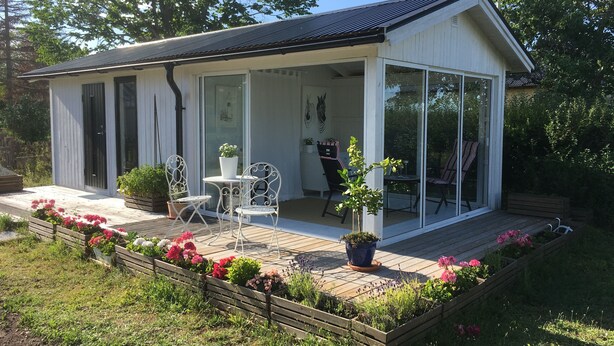 A small, single-story house with a covered porch, a sliding glass door, and a small patio area with a table and chairs.