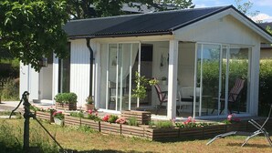 A white house with a glass conservatory, wooden deck, and potted plants.