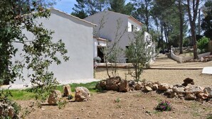 Un bâtiment à l’extérieur blanc, doté d’un petit jardin agrémenté de rochers et d’une végétation clairsemée.