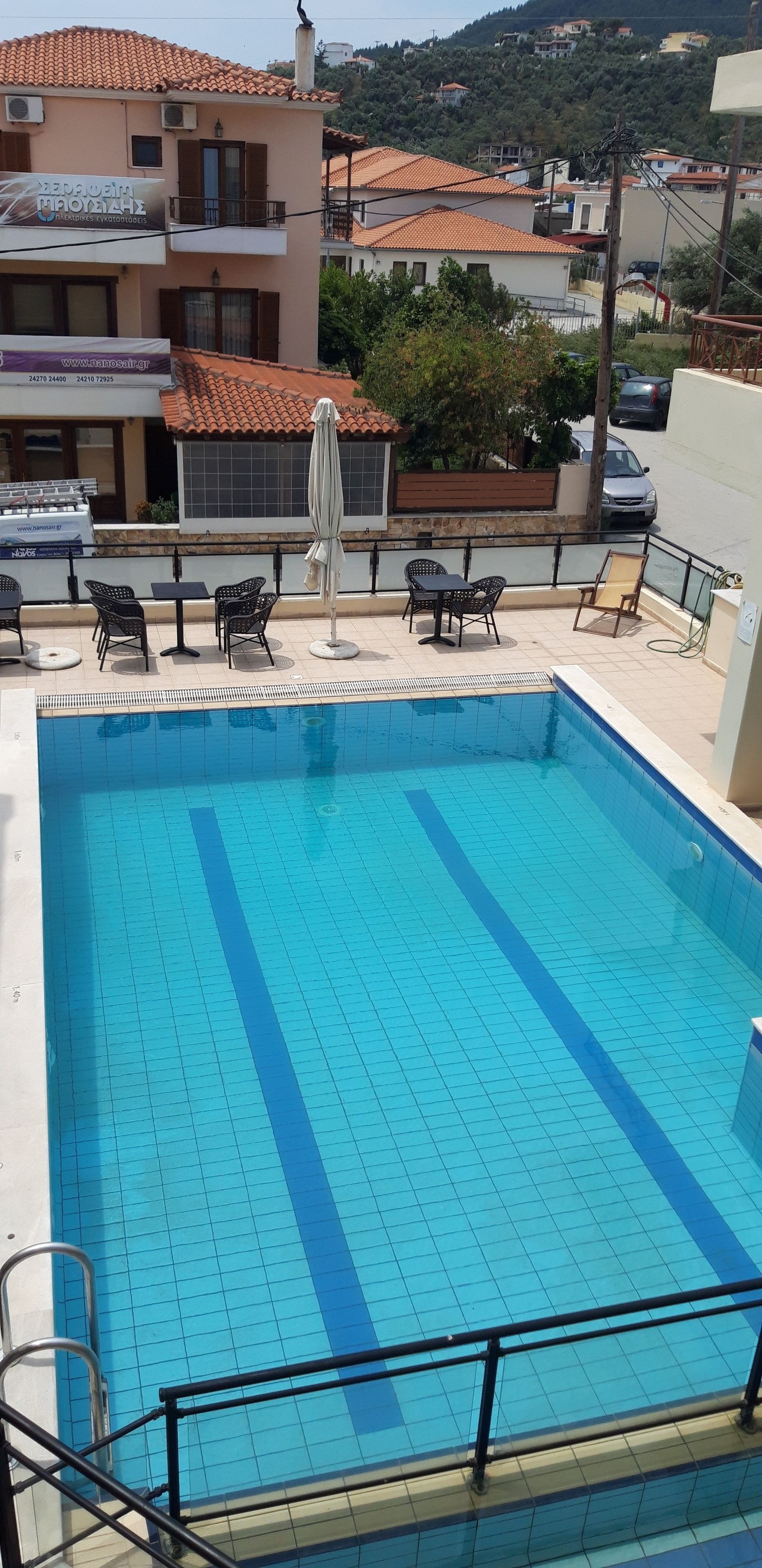 A swimming pool with tiled flooring, surrounded by outdoor furniture and a railing.