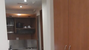 A compact kitchen with a built-in microwave, a wooden cabinet, and a chair. - Dabasis-Drolias (Skiathos)