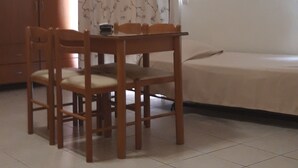 A room with a dining table and chairs, a bed, and a wardrobe. - Dabasis-Drolias (Skiathos)