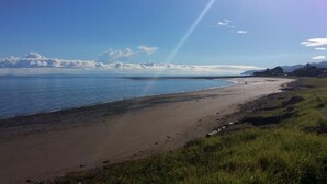 Een kuststrand met een heldere lucht en verre bergen.